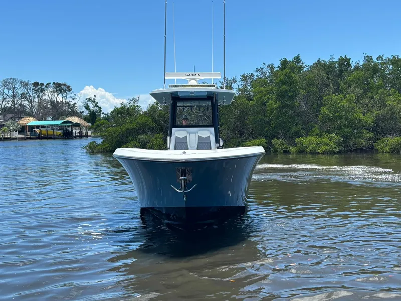 Slide: The Image of 2026 Invincible 36 Open Fisherman boat on calm water, surrounded by lush greenery. - 6