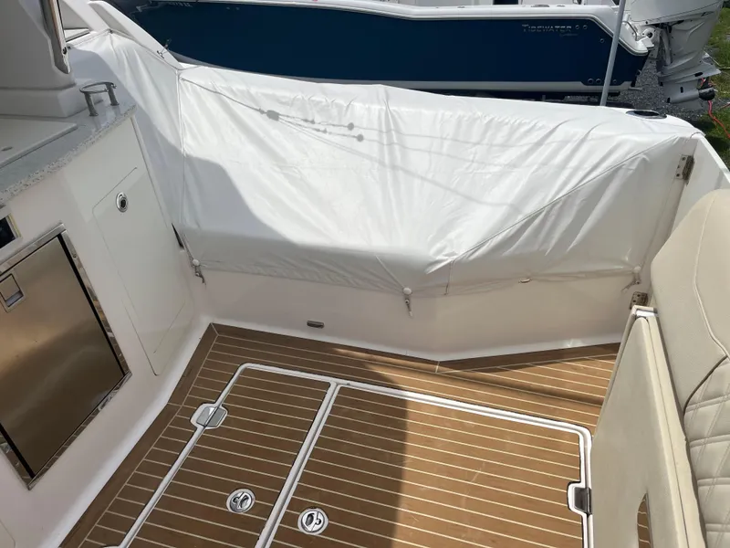 Slide: The Image of 2019 Regal 33 SAV boat interior with teak flooring and covered seating area. - 16