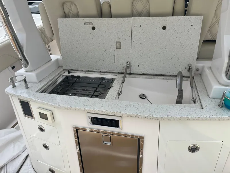 Slide: The Image of 2019 Regal 33 SAV boat kitchenette with sink, stove, and storage compartments. - 18