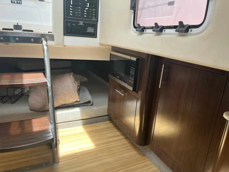 Slide: The Image of 2019 Regal 33 SAV interior with microwave, wooden cabinets, and cozy bedding area. - 28