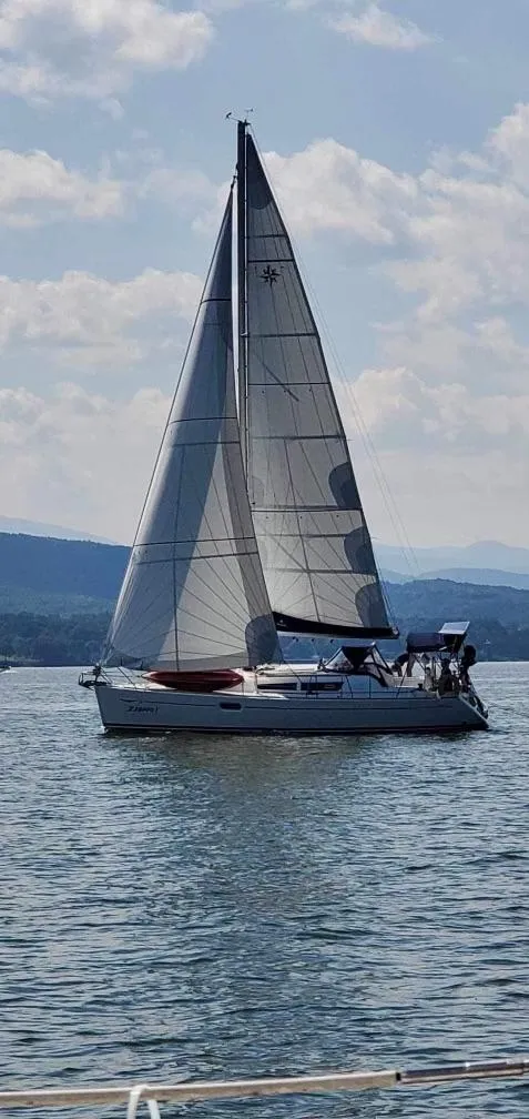 The Image of 2008 Jeanneau Sun Odyssey 36i sailboat on calm water under a partly cloudy sky. - 0