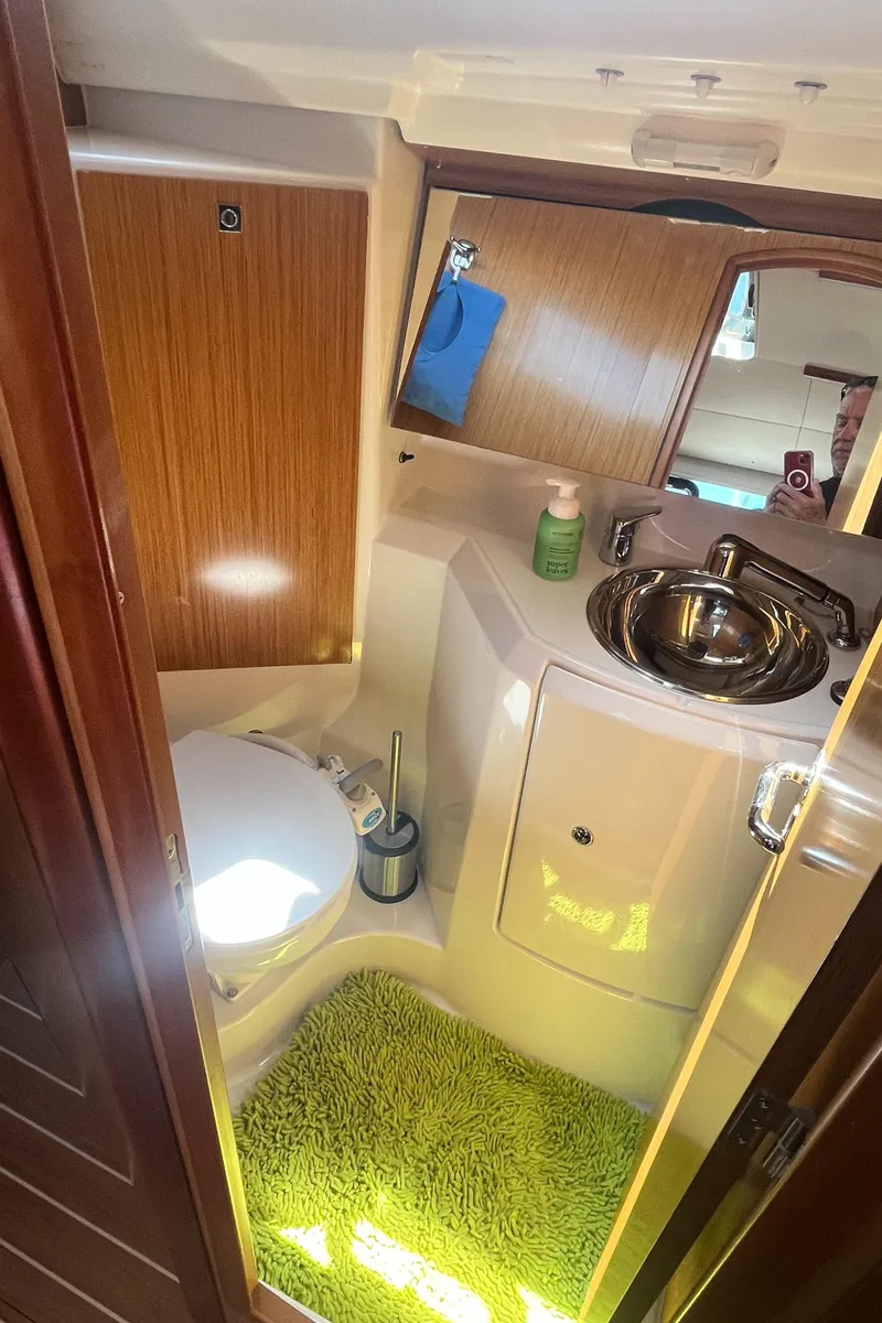 Slide: The Image of Interior of 2008 Jeanneau Sun Odyssey 36i yacht bathroom with sink, toilet, and green rug. - 15
