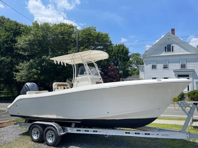 The Image of 2023 Cobia 237CC boat on trailer, parked outdoors under a clear blue sky. - 1