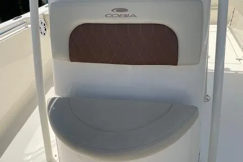 Slide: The Image of 2023 Cobia 237CC boat seat with brown cushion and logo. - 8