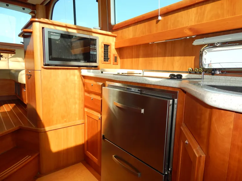 Slide: The Image of 2010 Sabre 40 Sedan yacht kitchen with wood cabinetry, microwave, and stainless steel fridge. - 25