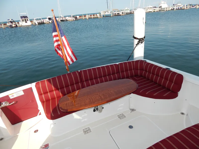 Slide: The Image of 2010 Sabre 40 Sedan yacht with red seating, wooden table, and American flag at marina. - 45
