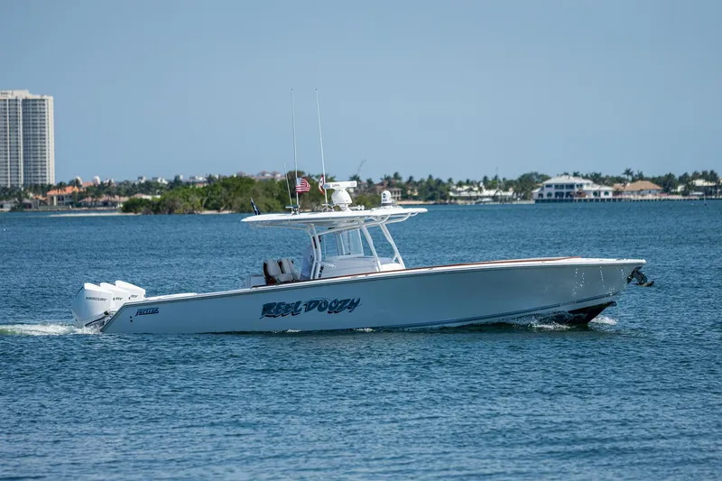 Slide: The Image of 2023 Jupiter 38 boat cruising on a sunny day near coastal buildings. - 2