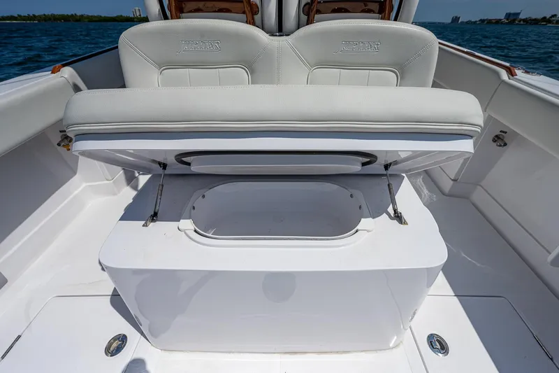 Slide: The Image of 2023 Jupiter 38 boat with open storage compartment, white seating, and ocean backdrop. - 21