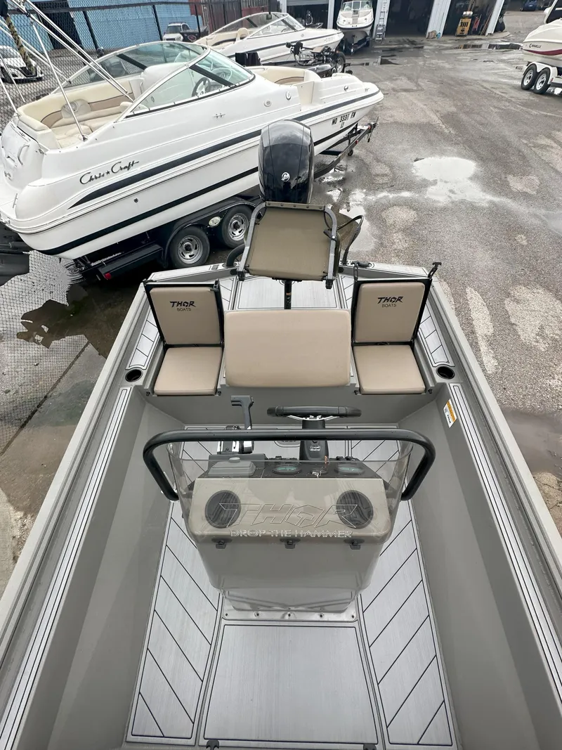 Slide: The Image of 2024 Thor 1900 Center Console boat with beige seating, parked near other boats. - 9