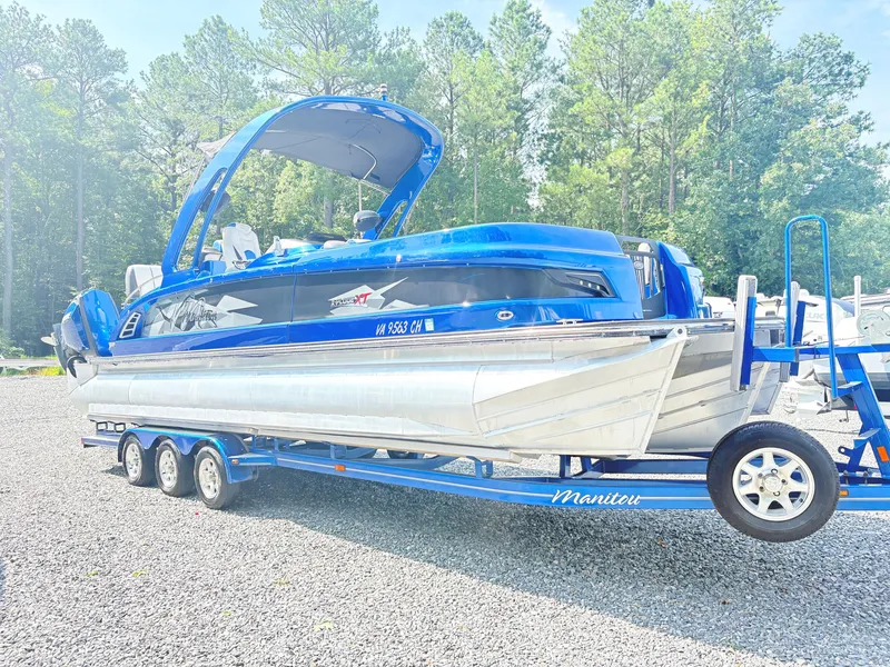 Slide: The Image of 2017 Manitou X-Plode Series 25 XT SRS SHP pontoon boat on trailer, surrounded by trees. - 4