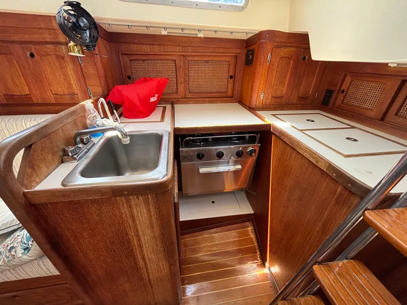 Slide: The Image of 1988 Bristol 33.3 yacht kitchen with wooden cabinetry, sink, stove, and compact design. - 16