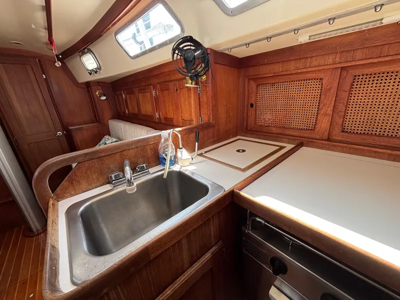 Slide: The Image of 1988 Bristol 33.3 yacht interior with wooden cabinetry, sink, and countertop in the galley area. - 19