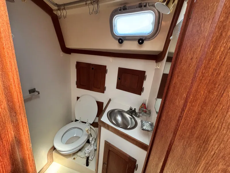 Slide: The Image of 1988 Bristol 33.3 yacht bathroom with wooden cabinets, toilet, and sink. - 22
