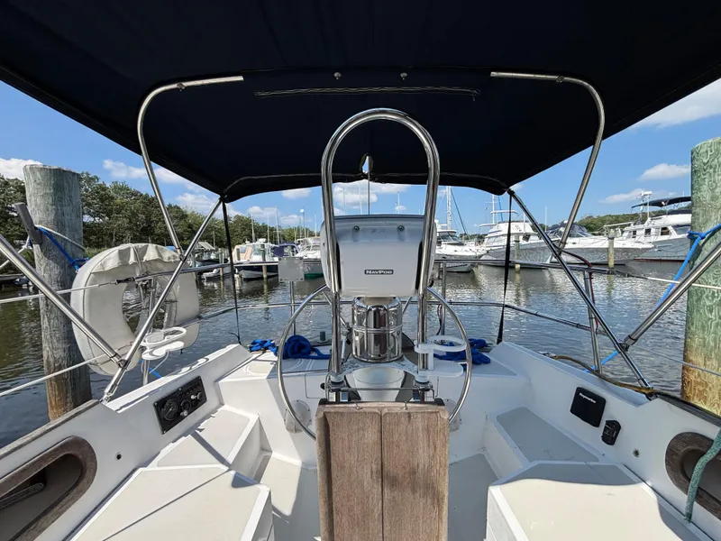 Slide: The Image of 1988 Bristol 33.3 sailboat cockpit with steering wheel, docked at marina under blue sky. - 31