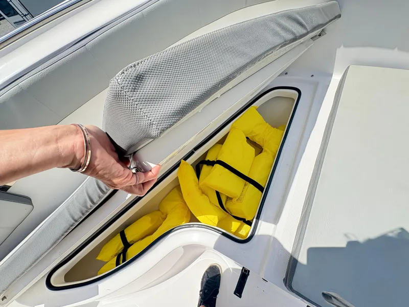 Slide: The Image of Storage compartment with yellow life jackets on a 2022 Aquasport 2300 CC boat. - 27
