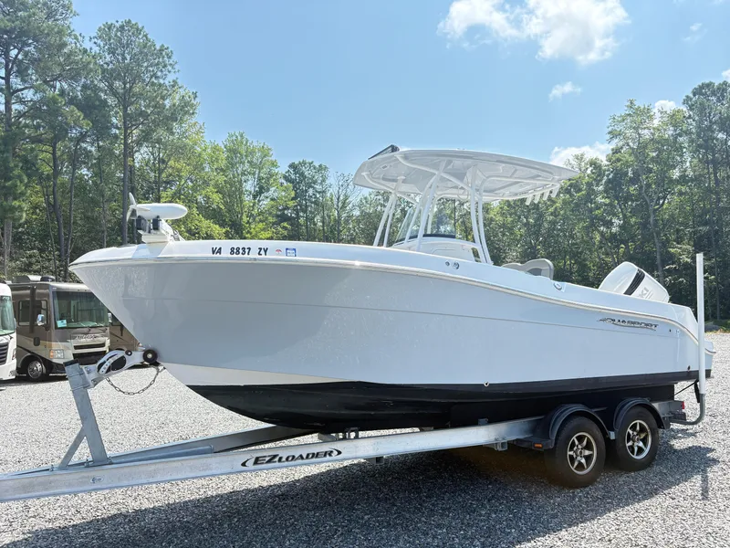 Slide: The Image of 2022 Aquasport 2300 CC boat on trailer, parked outdoors with trees in background. - 30