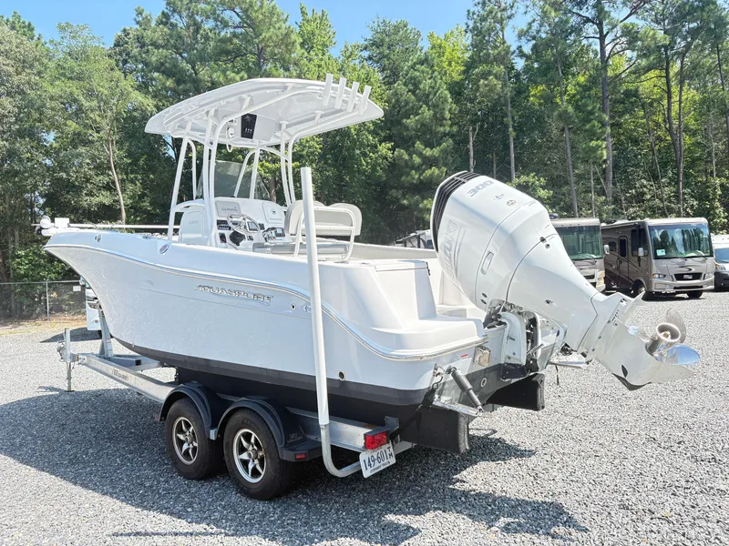 Slide: The Image of 2022 Aquasport 2300 CC boat on trailer, parked outdoors with trees in background. - 31