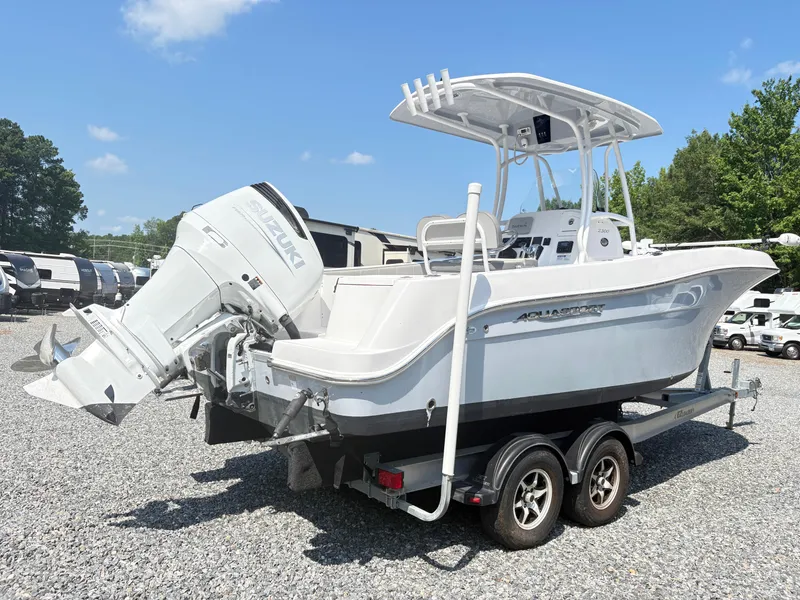 Slide: The Image of 2022 Aquasport 2300 CC boat on trailer with Suzuki outboard motor, parked outdoors. - 33