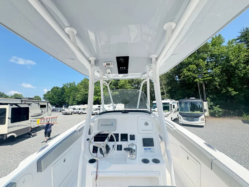 Slide: The Image of 2022 Aquasport 2300 CC boat interior with Garmin navigation, parked near RVs and trees. - 37