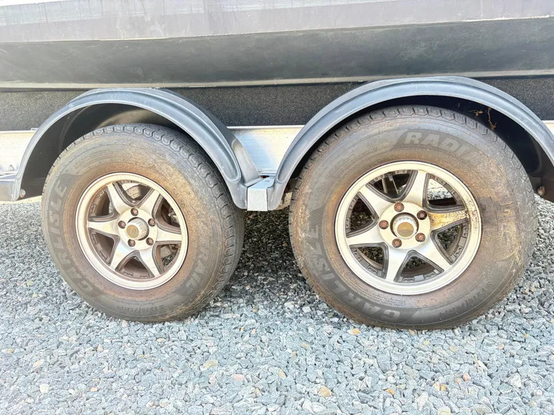 Slide: The Image of Trailer wheels of a 2022 Aquasport 2300 CC on gravel surface. - 38