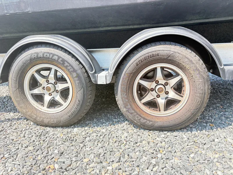 Slide: The Image of Trailer wheels of a 2022 Aquasport 2300 CC on gravel surface. - 39