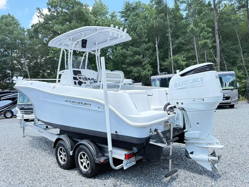 Slide: The Image of 2022 Aquasport 2300 CC boat with Suzuki engine on trailer, surrounded by trees. - 4