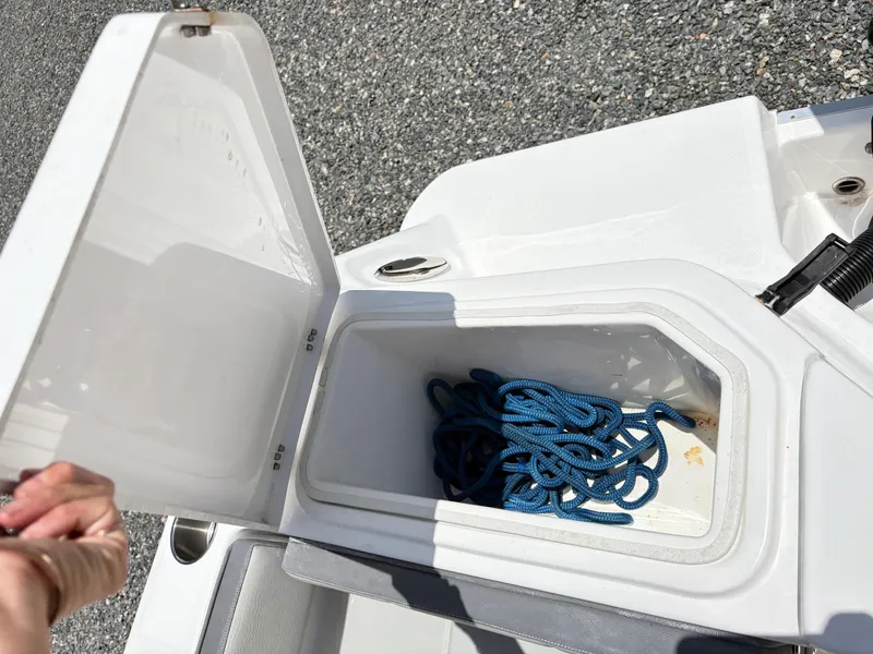 Slide: The Image of Open storage compartment on 2022 Aquasport 2300 CC boat with blue rope inside. - 6