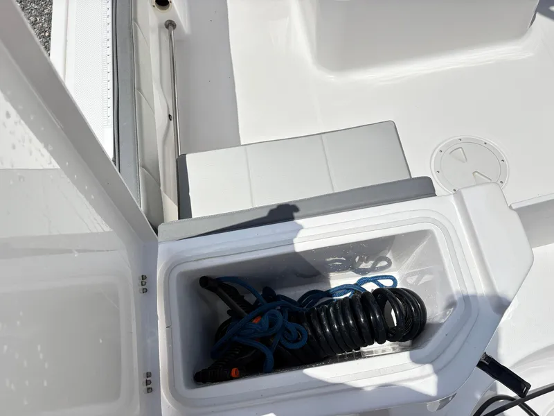 Slide: The Image of Open storage compartment on 2022 Aquasport 2300 CC boat with coiled rope inside. - 7