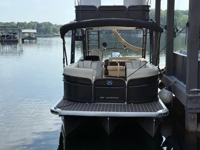 Slide: The Image of 2022 Premier 250 Sunsation pontoon boat docked on a calm lake. - 2