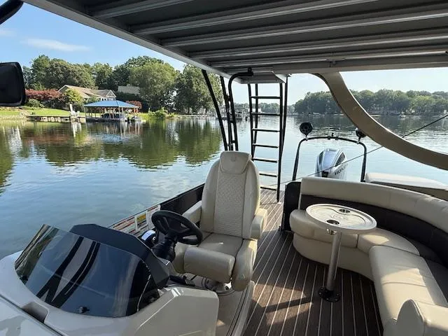 Slide: The Image of 2022 Premier 250 Sunsation pontoon boat interior with seating, steering console, and lake view. - 21