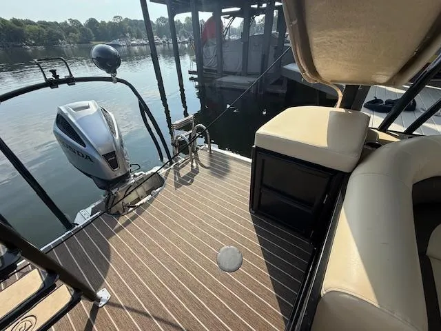 Slide: The Image of 2022 Premier 250 Sunsation boat interior with seating and outboard motor, docked by calm water. - 23