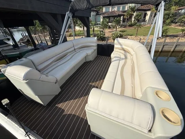Slide: The Image of 2022 Premier 250 Sunsation pontoon boat with spacious seating and cup holders, docked by a waterfront. - 26