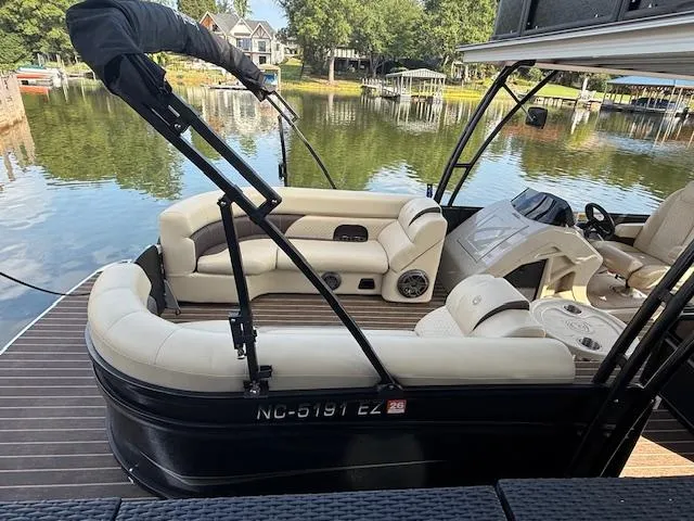 Slide: The Image of 2022 Premier 250 Sunsation pontoon boat with beige seating, docked on a serene lake. - 3