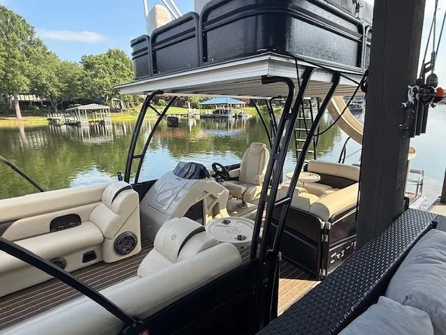 Slide: The Image of 2022 Premier 250 Sunsation pontoon boat with luxurious seating on a serene lake. - 6