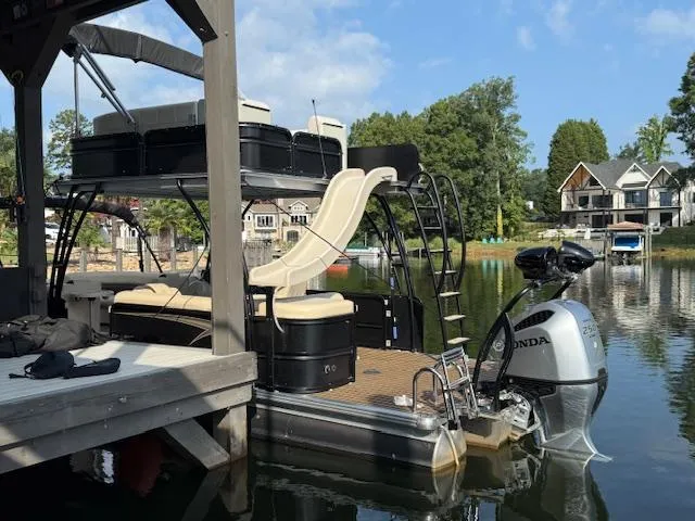 Slide: The Image of 2022 Premier 250 Sunsation pontoon boat with slide, docked on a serene lake. - 8