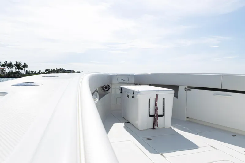 Slide: The Image of 2021 SeaVee 390 boat deck with cooler, clear sky, and distant palm trees. - 25
