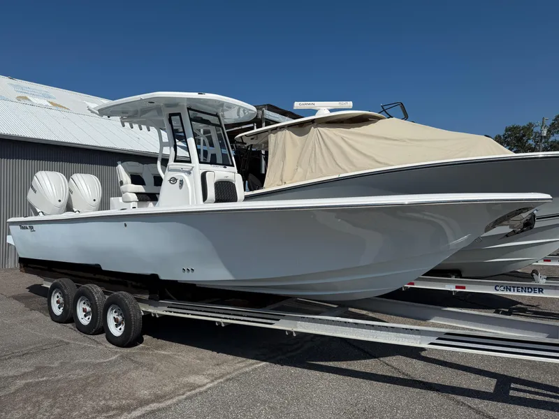The Image of 2026 Tidewater 2700 Carolina Bay boat on trailer, parked outdoors under clear blue sky. - 1