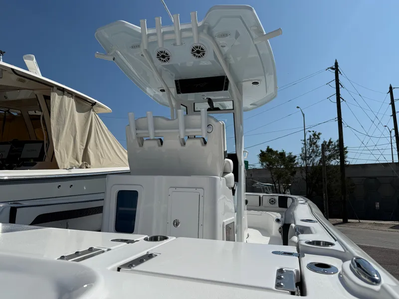 Slide: The Image of 2026 Tidewater 2700 Carolina Bay boat with T-top and rod holders, docked under clear sky. - 17