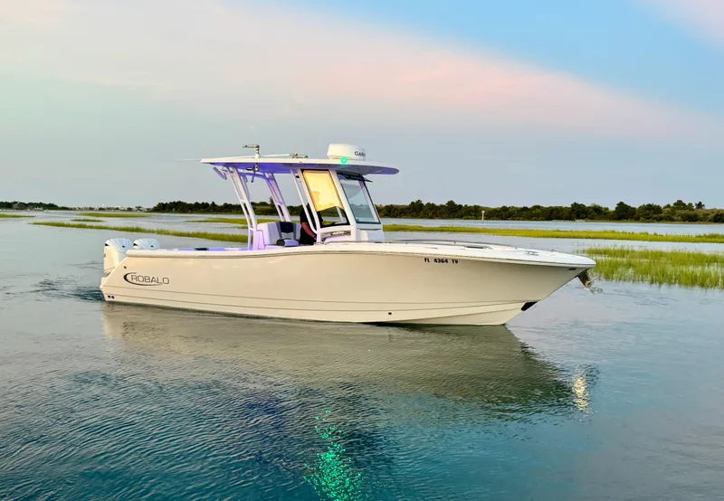 Slide: The Image of 2024 Robalo R270 Center Console boat on calm water at sunset. - 2