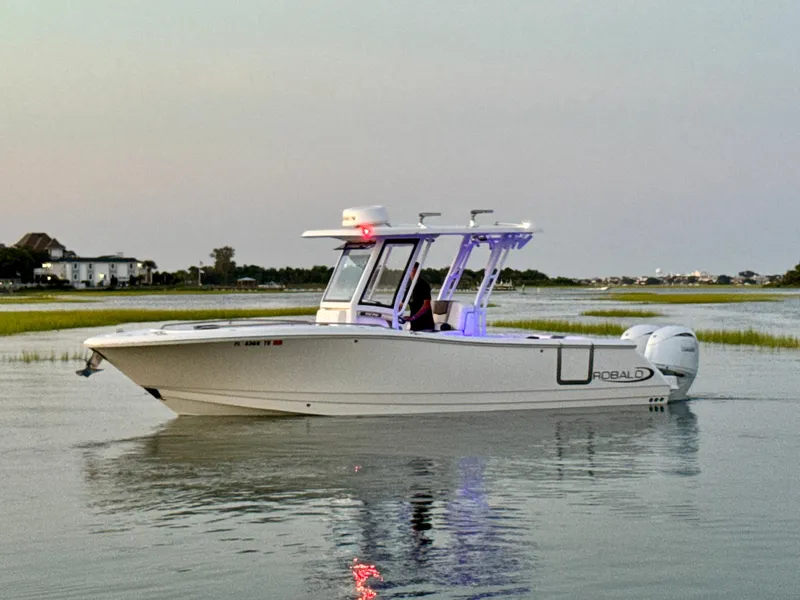 Slide: The Image of 2024 Robalo R270 Center Console boat on calm water at sunset. - 4