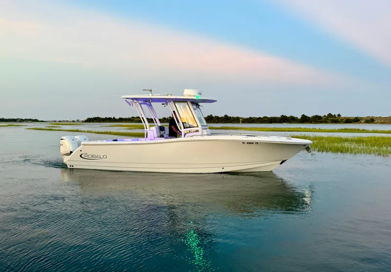 Slide: The Image of 2024 Robalo R270 Center Console boat on calm water at sunset. - 6