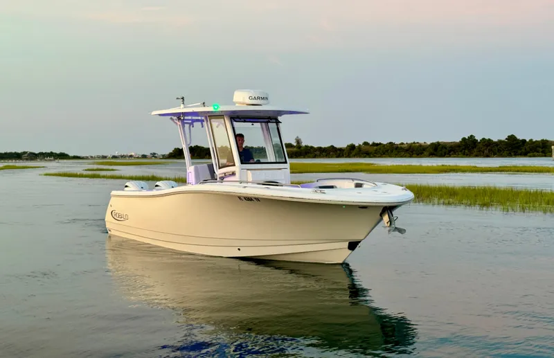Slide: The Image of 2024 Robalo R270 Center Console boat cruising on calm waters at sunset. - 7