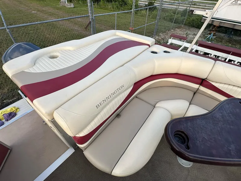Slide: The Image of 2009 Bennington 2577RFi boat interior with cream and maroon seating, cup holders, and table. - 5