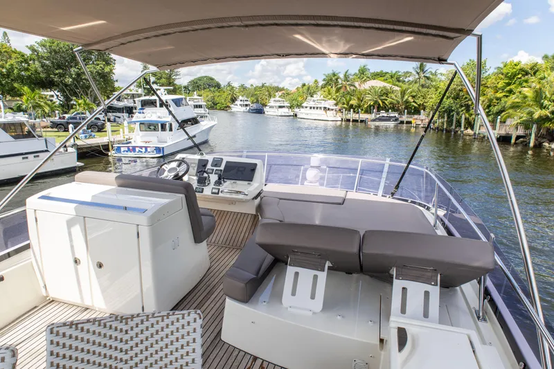 Slide: The Image of Flybridge view of 2018 Prestige 500 yacht, featuring helm and seating area, docked in a marina. - 31