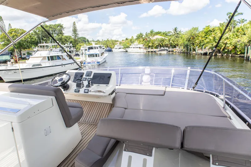 Slide: The Image of Flybridge view of 2018 Prestige 500 yacht, featuring helm and seating, docked in a marina. - 32