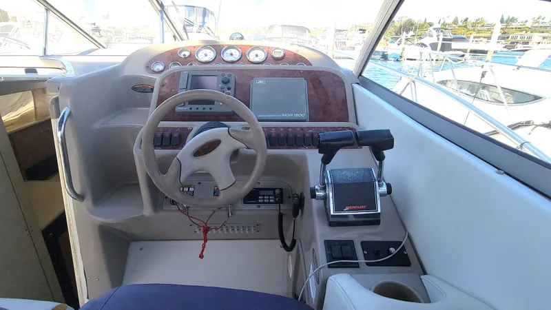 Slide: The Image of 2001 Bayliner 3055 Ciera helm with steering wheel, controls, and gauges in a marina setting. - 10