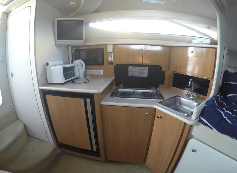 Slide: The Image of 2001 Bayliner 3055 Ciera boat kitchen with stove, sink, microwave, and compact fridge. - 15