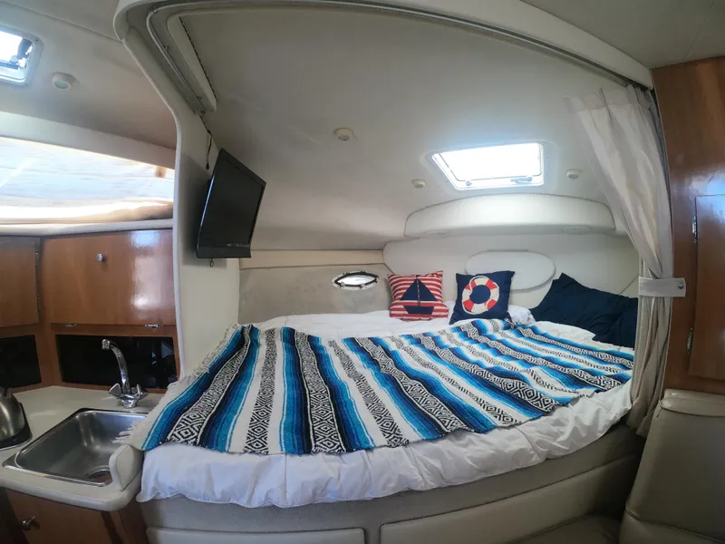 Slide: The Image of 2001 Bayliner 3055 Ciera cabin interior with bed, striped blanket, and nautical-themed pillows. - 16