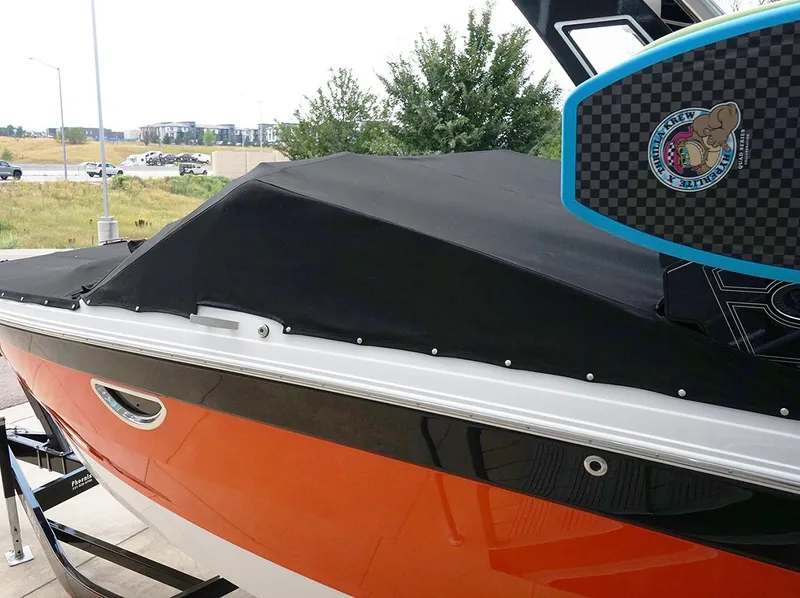 Slide: The Image of 2022 Cobalt R6 Surf boat with black cover and orange hull, parked outdoors. - 3