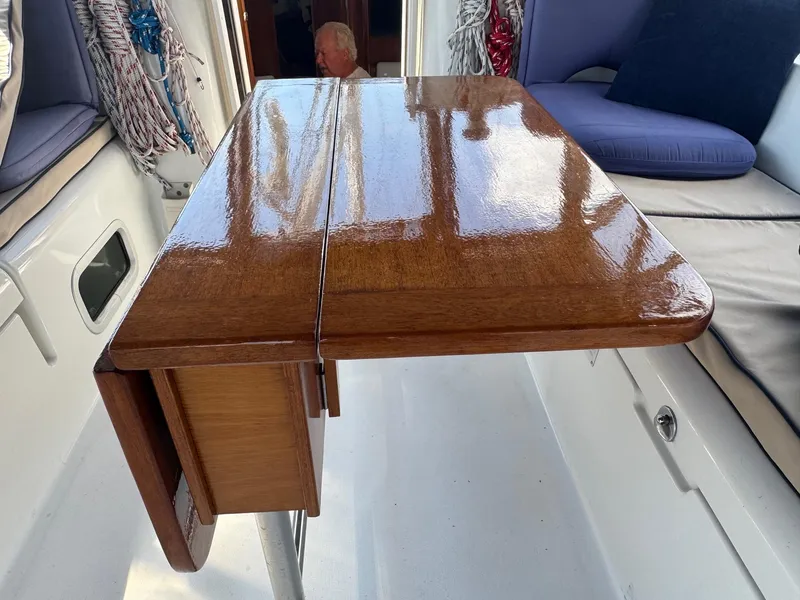 Slide: The Image of Polished wooden table on 2005 Beneteau Oceanis Clipper 473 yacht, with cushioned seating and nautical ropes. - 15